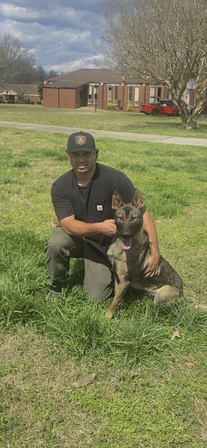 Colton Madrigal kneeling beside a dog outdoors